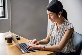 A woman is doing work on a laptop.