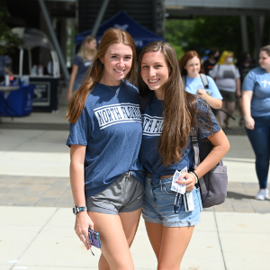 Two female students in UNF tshirts standing together and smiling