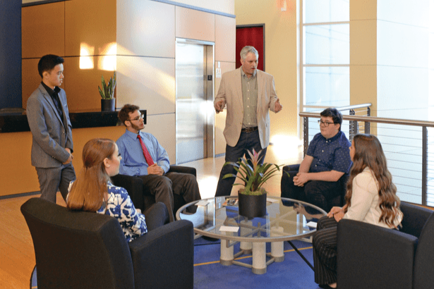 professional talking to a group of students in a lobby