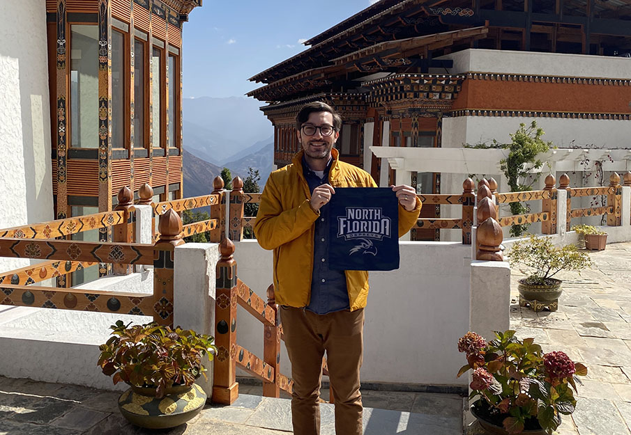 Dr. Josh Gellers posing with a University of North Florida merchandise in Bhutan