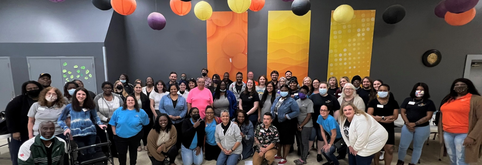 Large group photo of the OCT Arc Jacksonville staff with orange, purple and yellow lanterns above them