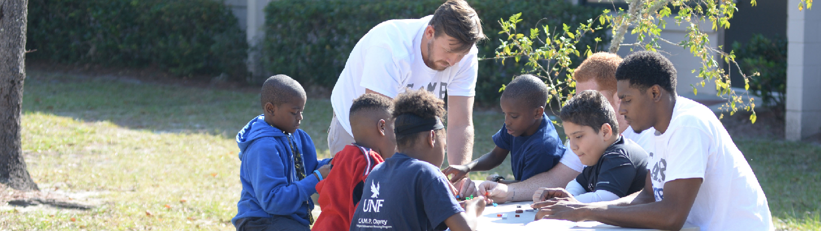 UNF students playing Legos with K12 students at an outside table