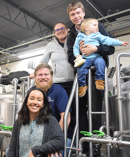 owners of historically hoppy posing with families in front of brewing equipment