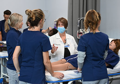 An instructor teaching three students in the sim lab