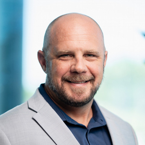 Bald white male with beard wearing light gray suit jacket smiling