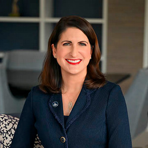 Woman in navy suit with brown hair smiling at camera