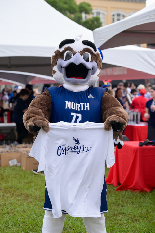 Ozzie mascot holding white T shirt with Ospreys Heart Walk design