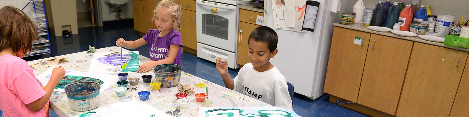 Three children painting in classroom