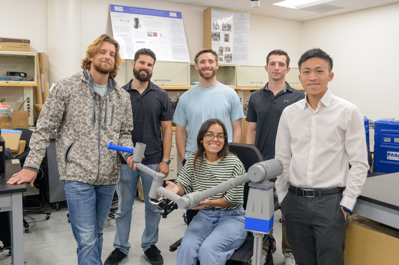 Engineering students presenting robotic arm