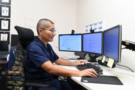 Asian man with glasses sitting at computer