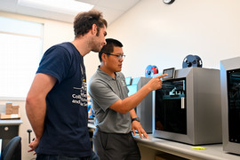Two men looking at screen, 2nd man is pointing at it