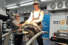 Man with sunglasses on indoor treadmill, woman watching