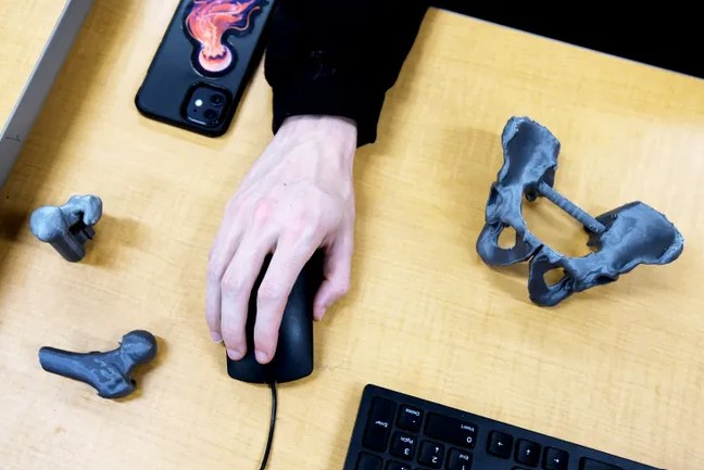 Hand on computer mouse next to 3D printed bones