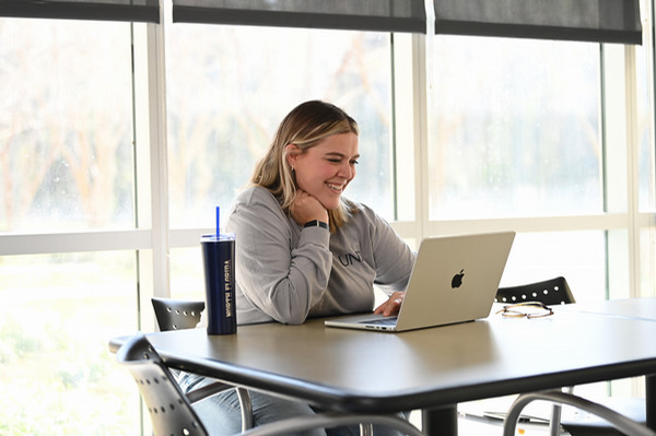 Student smiling while working on laptop