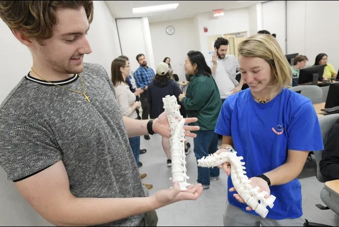 Two UNF students holding 3D printed spine