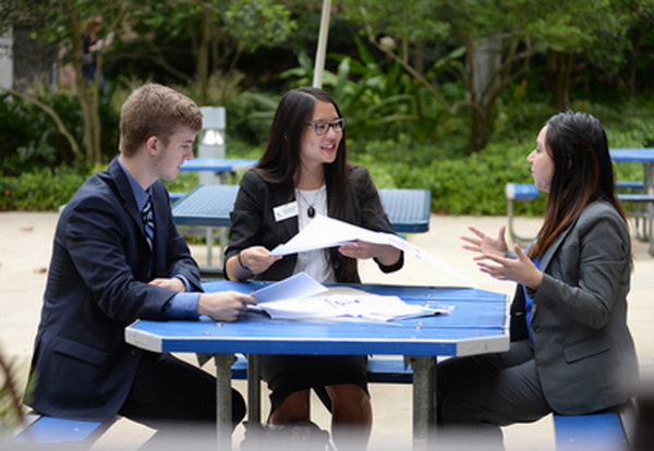 Three students talking while sitting at picnic table