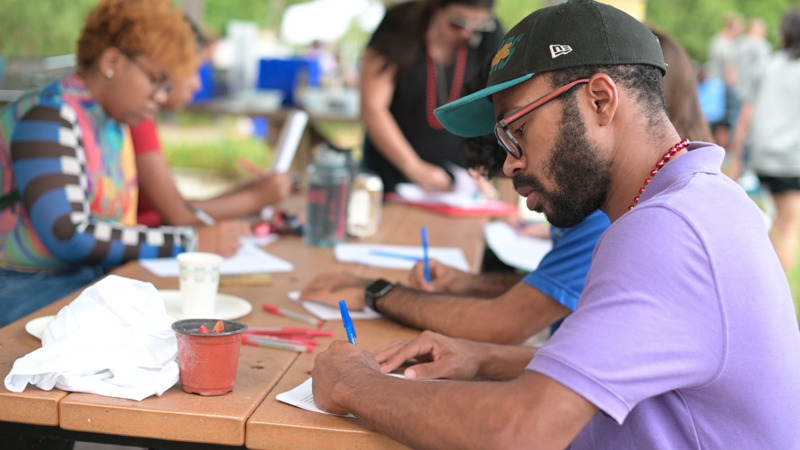 Student drawing on paper on a picnic table