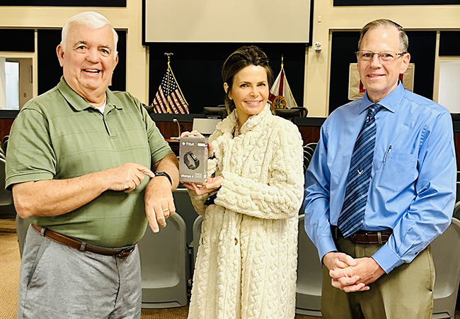 Julie Merten showing off a Fitbit with two men