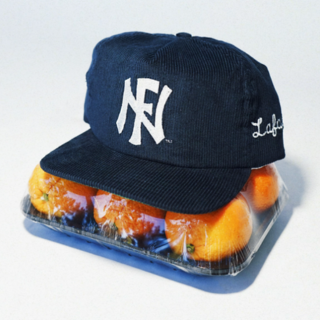 A blue UNF hat sits on top of a container of oranges