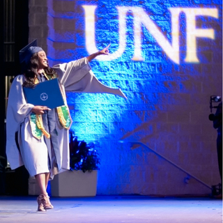 UNF graduate walks off stage with diploma. 