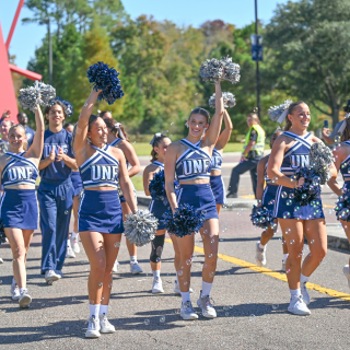 Cheerleaders smiling, pompoms waving in air, bubbles in forefront 