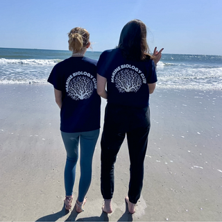 Two girls stand in front of ocean 
