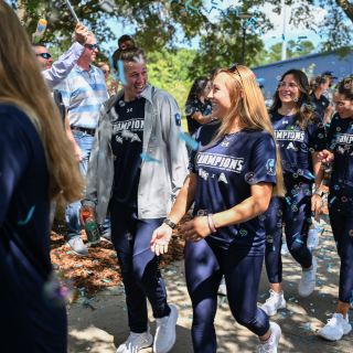 Softball sendoff, two players smile at each other with blue confetti falling around them