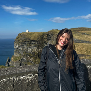 Female student smiling with cliffs and grass behind her