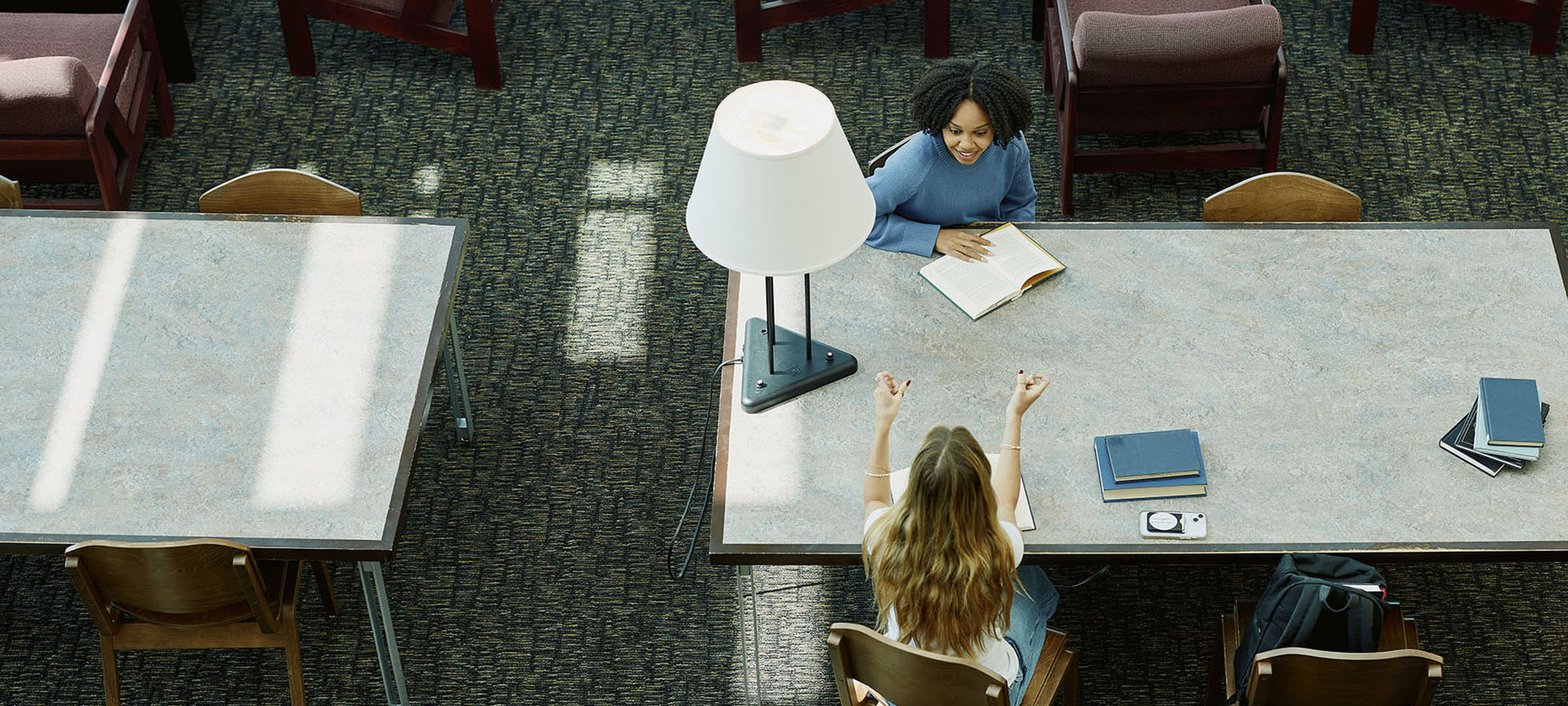 two students talking at a table in the library