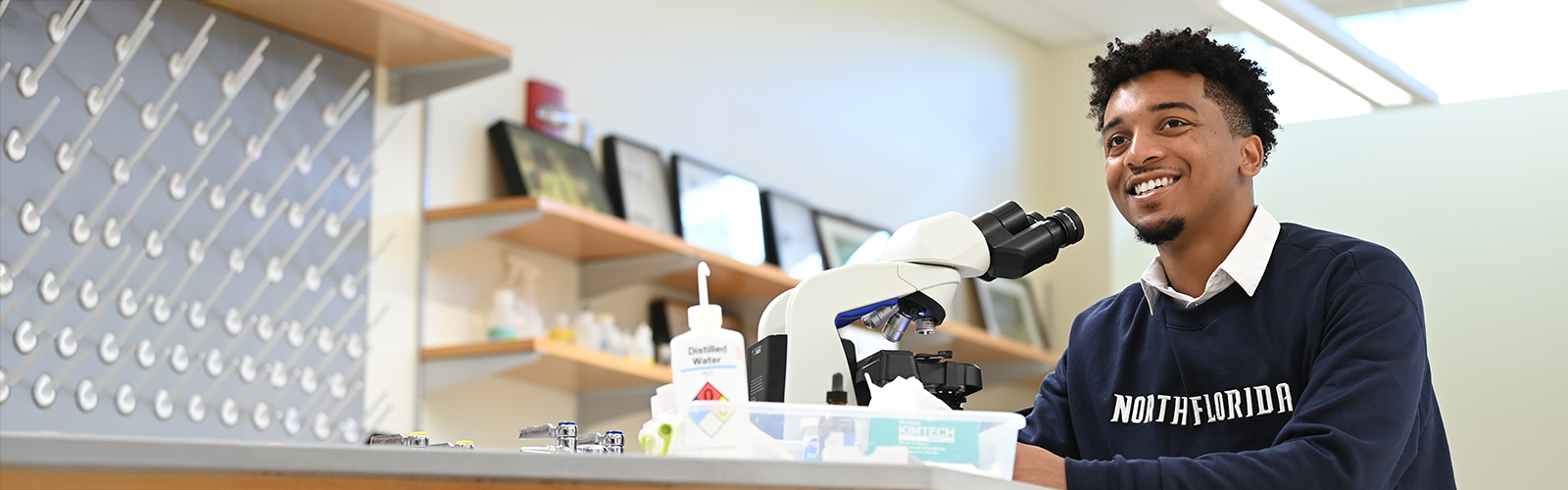 student at a microscope in a classroom