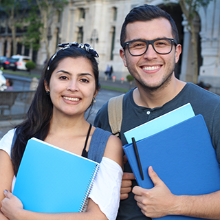 two students holding folders on a city street