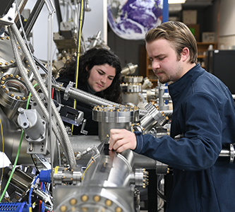 two students working on a piece of machinery