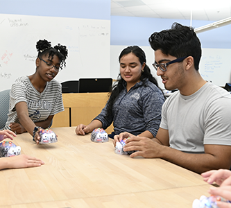 three students working with small robots