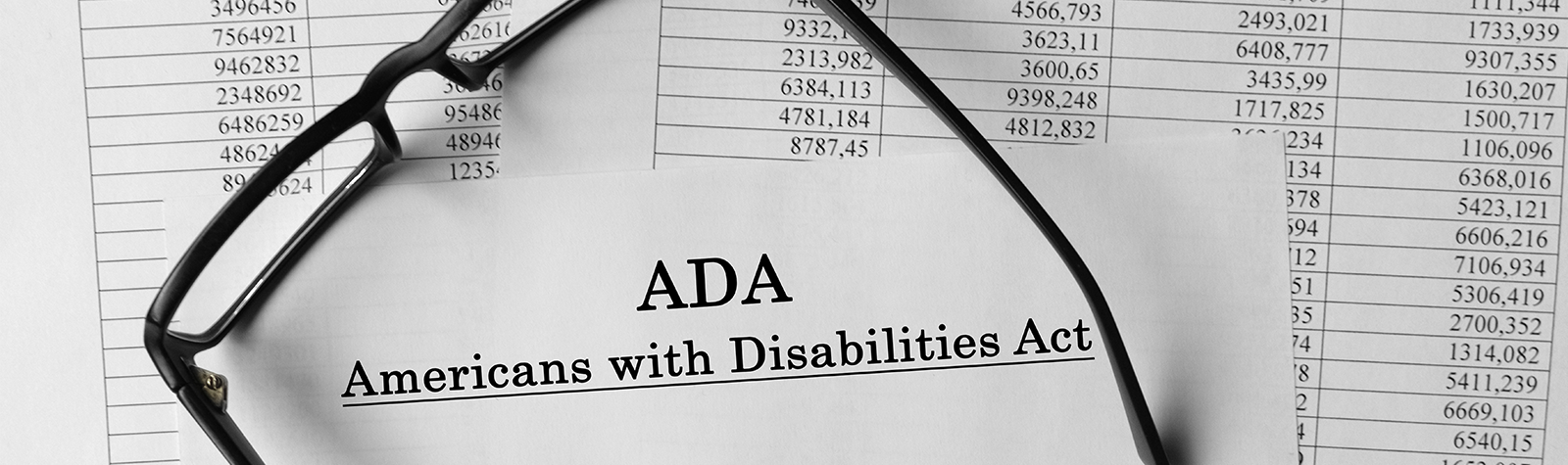 Glasses on spreadsheet full of numbers and text of ADA Americans with Disabilities Act