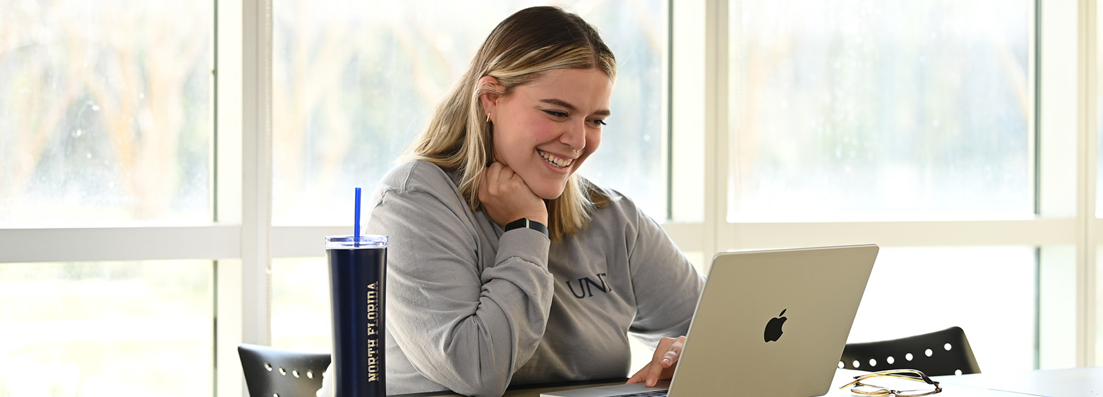 A student working on a laptop and smiling