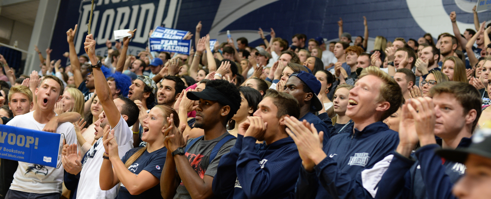 Large group of students in the UNF gym cheering on the basketball team