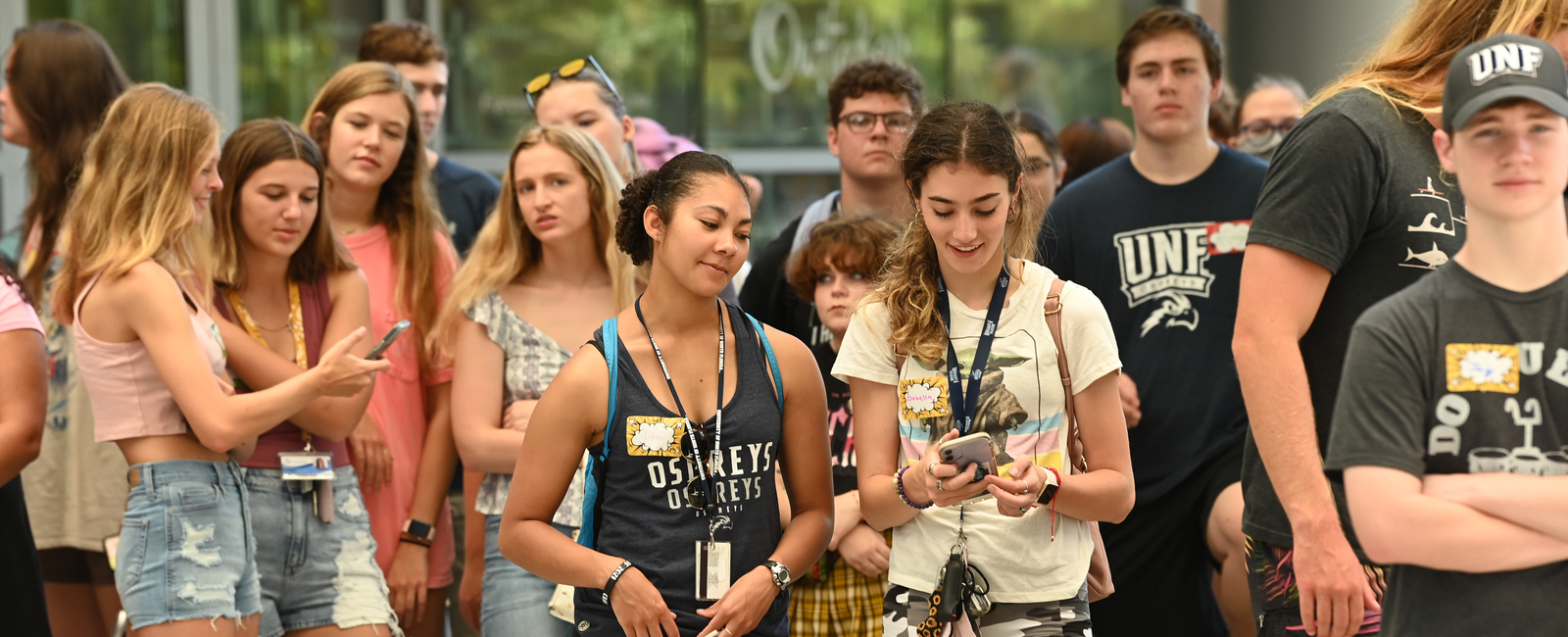 Group of students candidly standing together with some of them looking at their cellphones