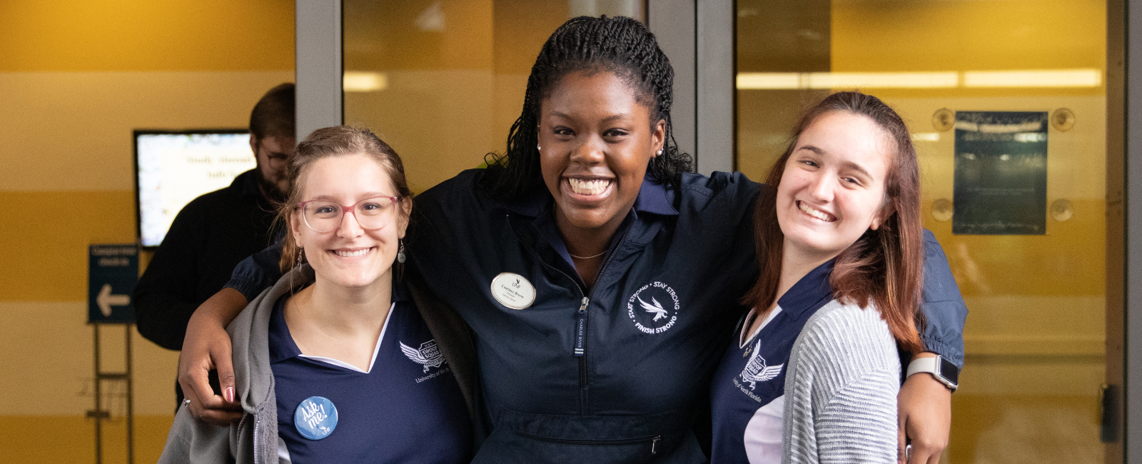 Three female student workers bundled together in UNF attire and smiling