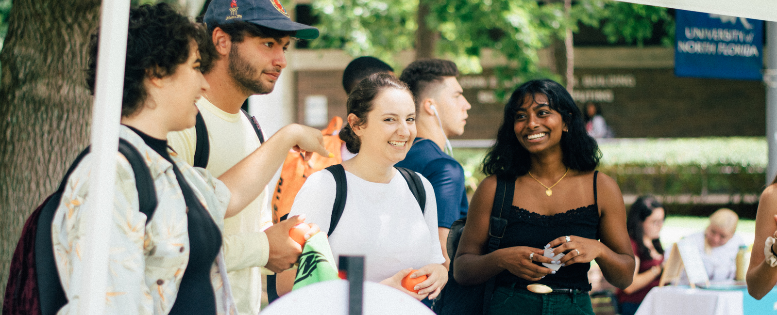 Group of students outside on campus having a conversation while smiling at one another