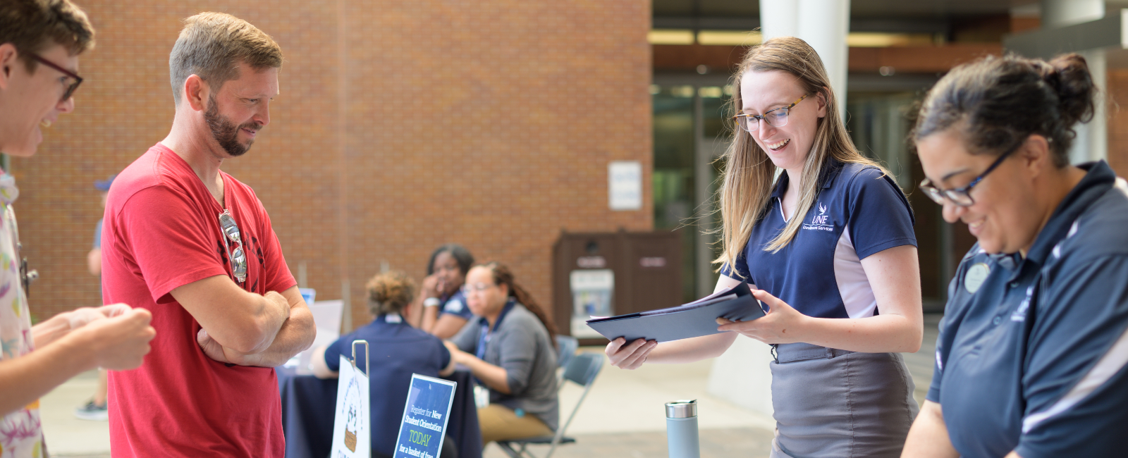 Father and son at an admissions table getting information from two UNF admissions staff members