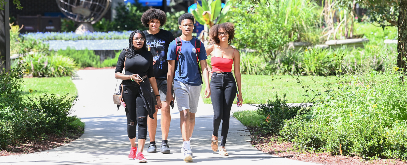 Group of four students walking through UNF's campus together