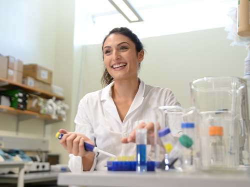 Female student in a white lab coat holding medical utensils in a labratory