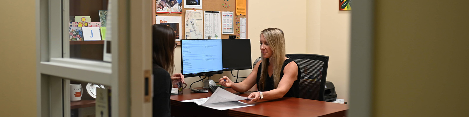 Advisor showcasing a brochure to a student in her office