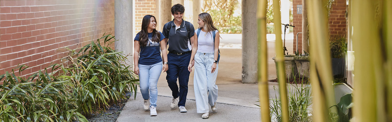 three students walking through the bamboo garden