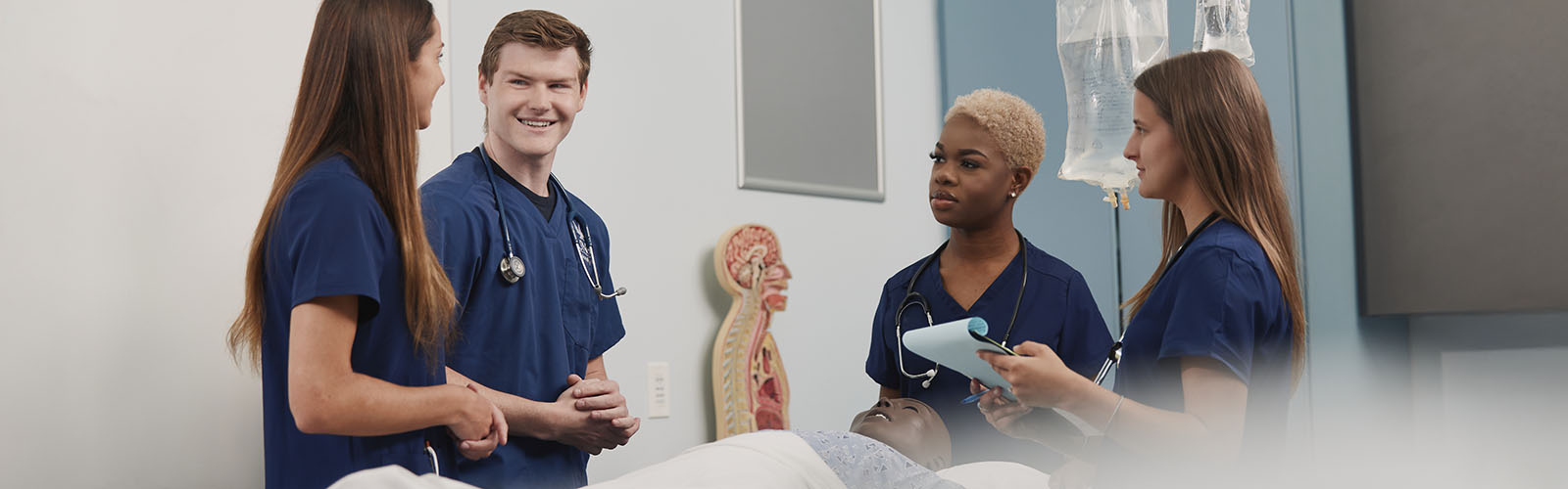 four nursing students talking in a simulation lab