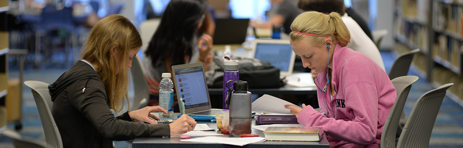 Two female students studying at a table in the library