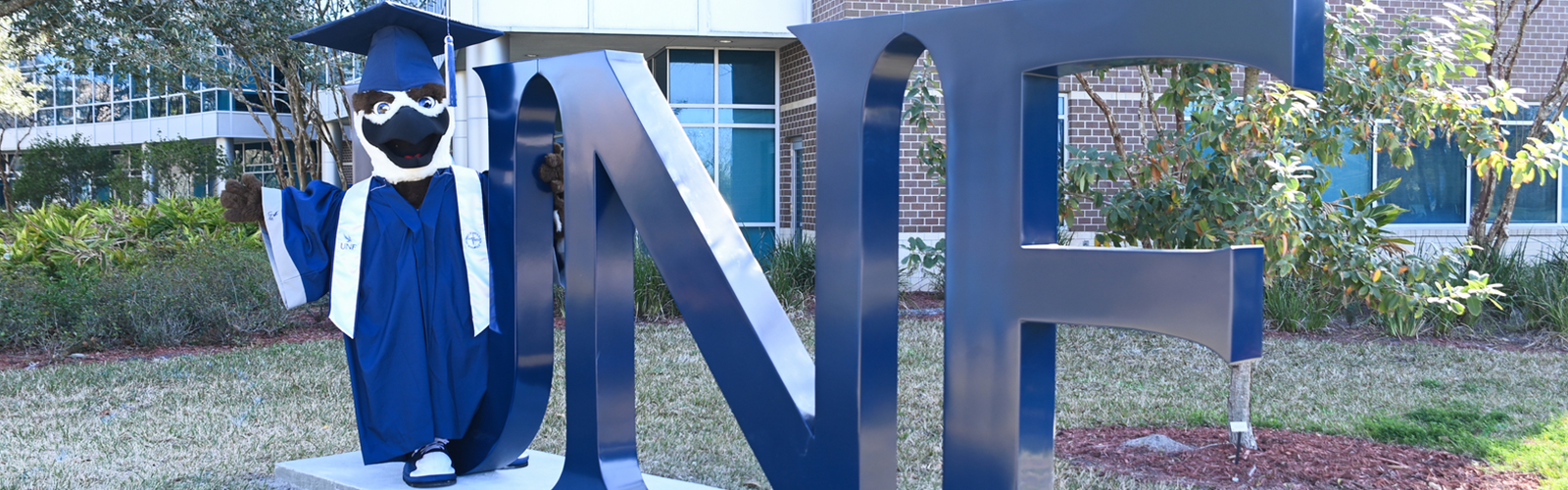 Ozzie standing on the UNF sign