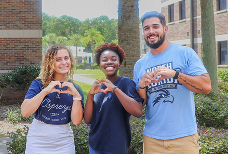 three students making heart symbols with their hands
