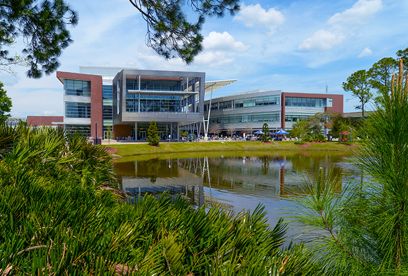 Student union building with tents and student walking around it and a pond in the foreground