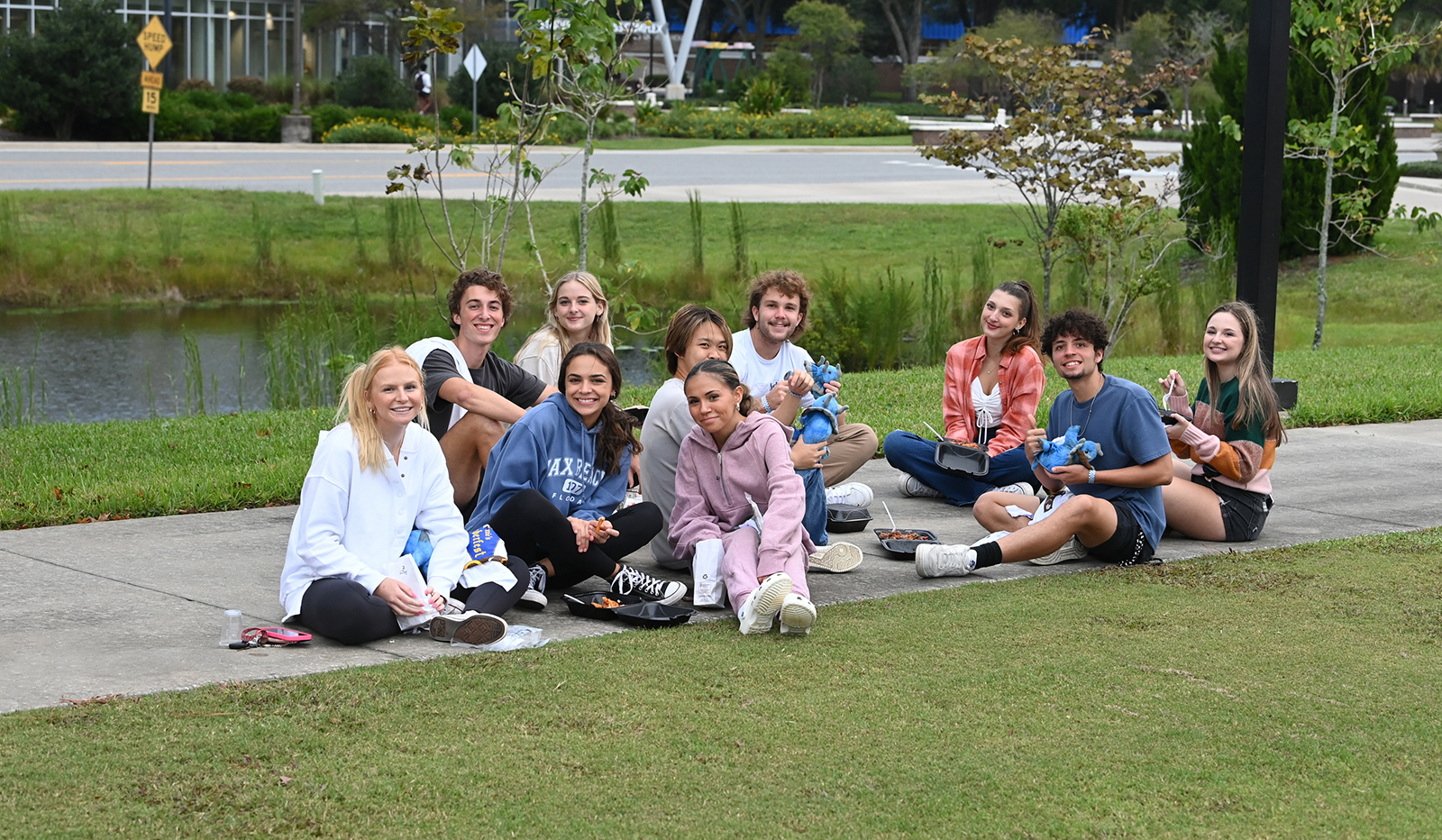 group of students sitting on the sidewalk eating together